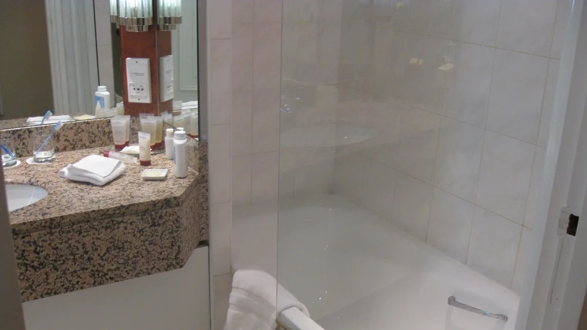 Accessible hotel bathroom with grab-friendly fittings, a wall-mounted grab bar beside the toilet and an open transfer space beside the fixtures