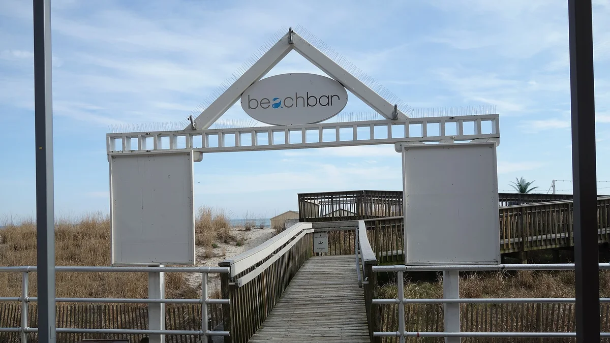Wide wooden ramp connecting the Atlantic City Boardwalk down to the beach beside a beach bar