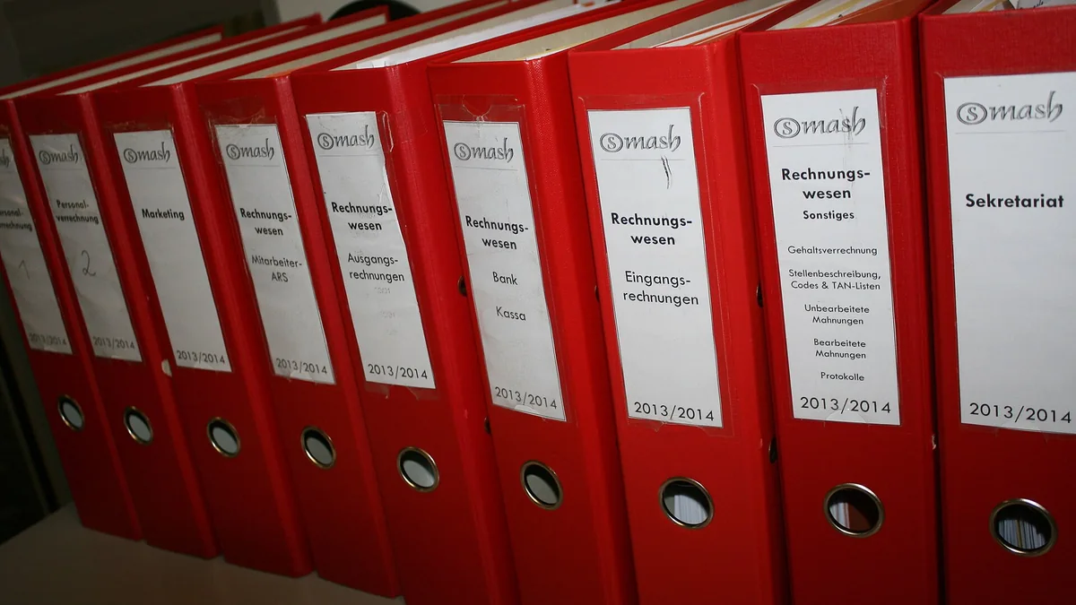 A row of red office binders on a shelf