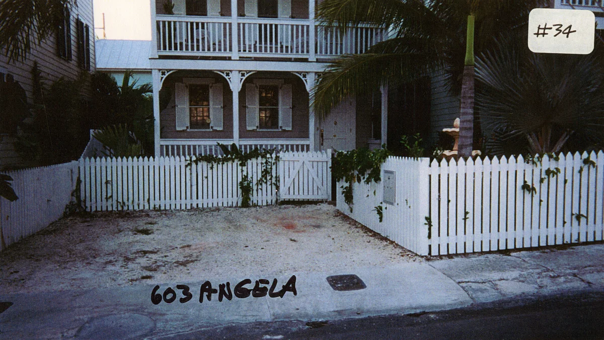A residential street in Key West, Florida, with a white picket fence and historic homes