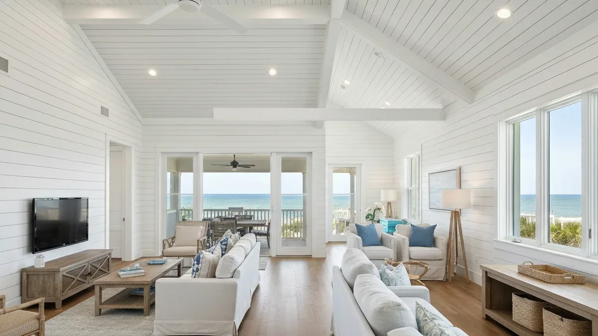 A bright coastal-modern beach house interior with shiplap walls and a Gulf view through large windows