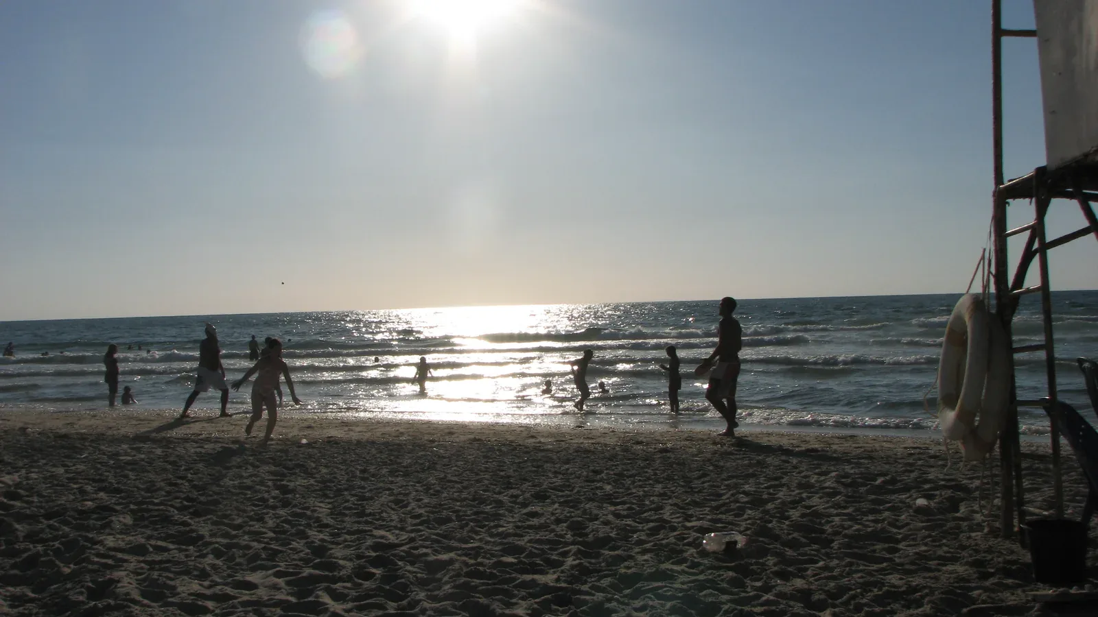 Families playing together on a beach in low golden sunlight