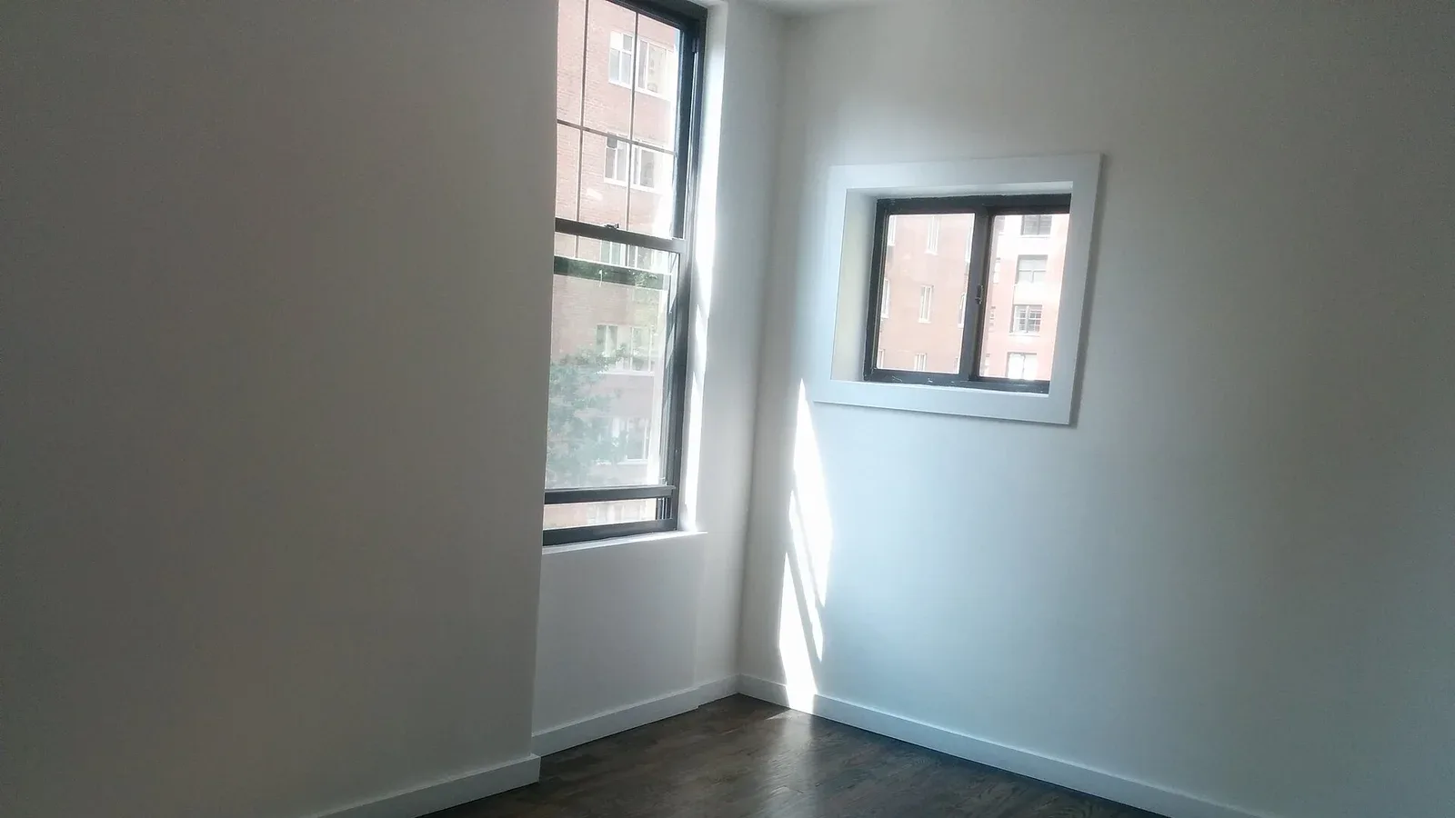 An empty apartment room with corner windows, a blank canvas before furnishing