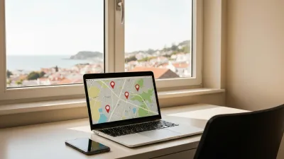 A bright home office with a laptop showing an abstract map with location pins and a smartphone beside it, a coastal town through the window
