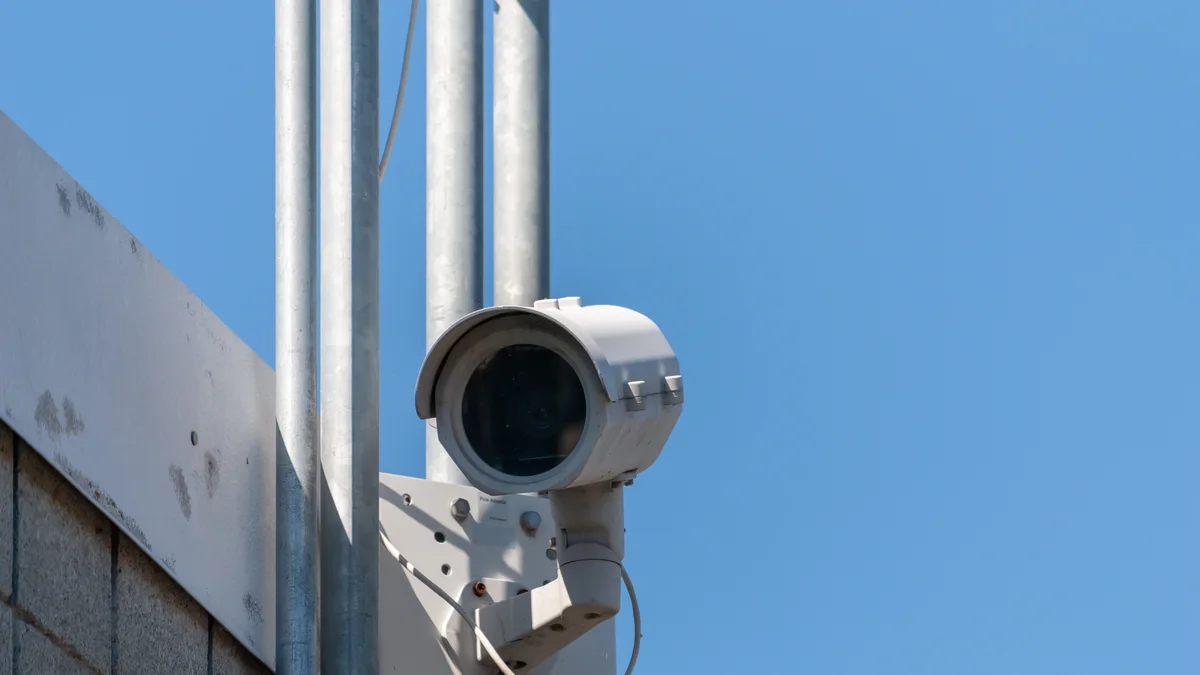 An exterior security camera mounted outdoors against a blue sky
