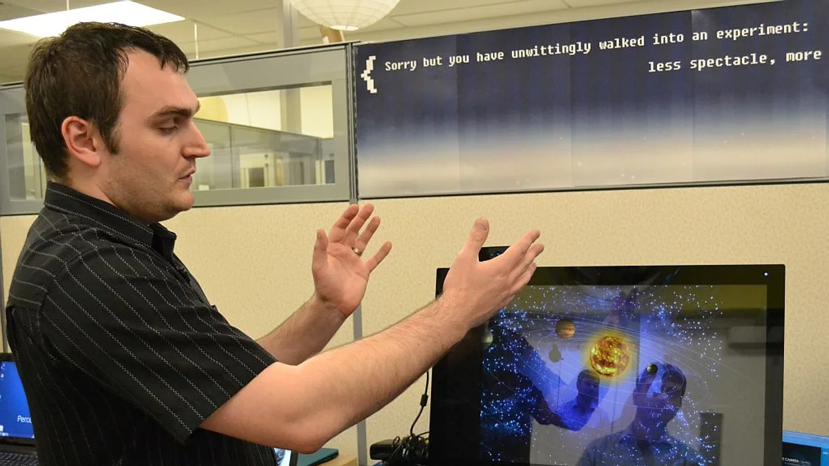 A person controlling a computer with hand gestures in a technology lab