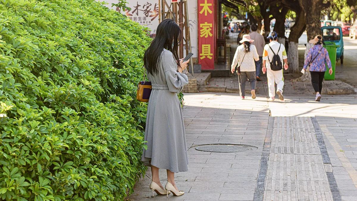 A woman looking at her phone on a city street