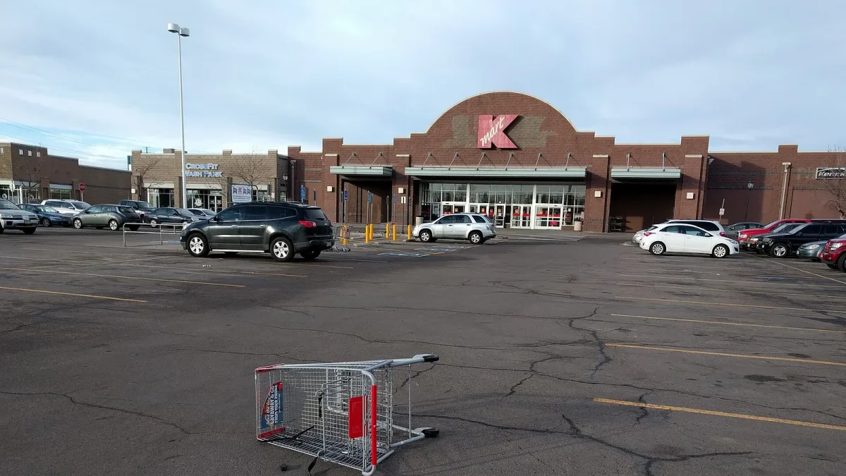 A single shopping cart left in an empty store parking lot
