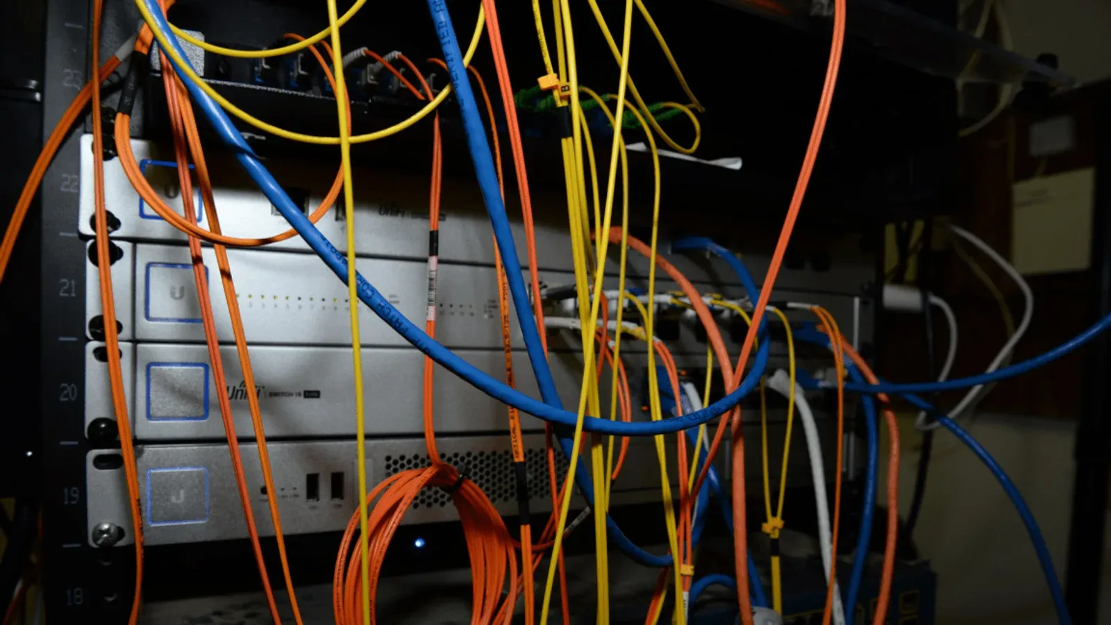 A server rack crowded with tangled coloured network cables