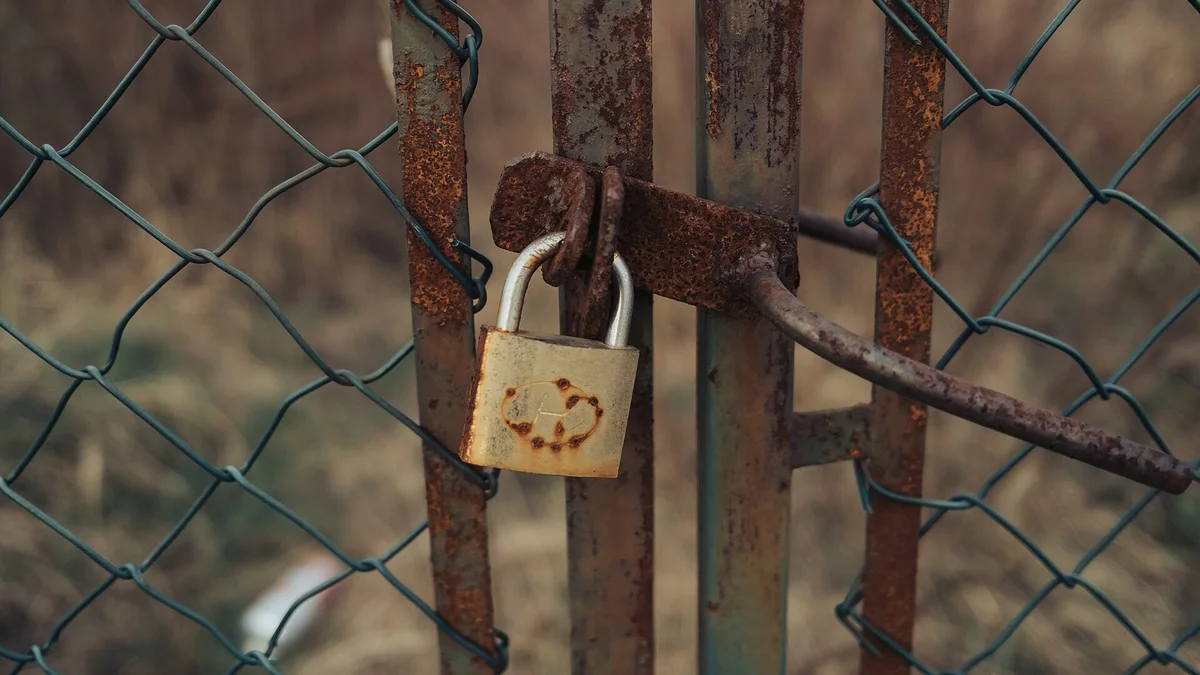 A rusted padlock securing an old metal gate