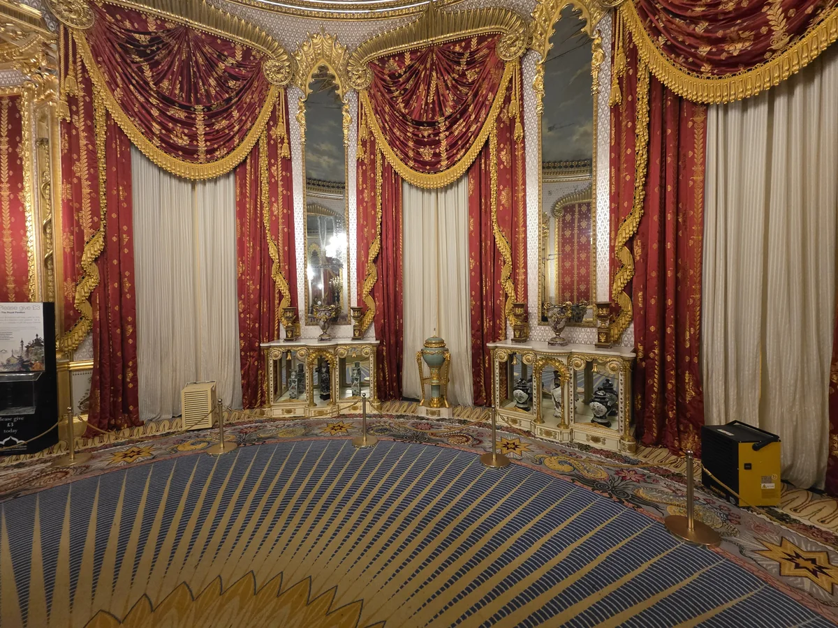 Red and gold curtains hung floor to ceiling around windows above a patterned carpet