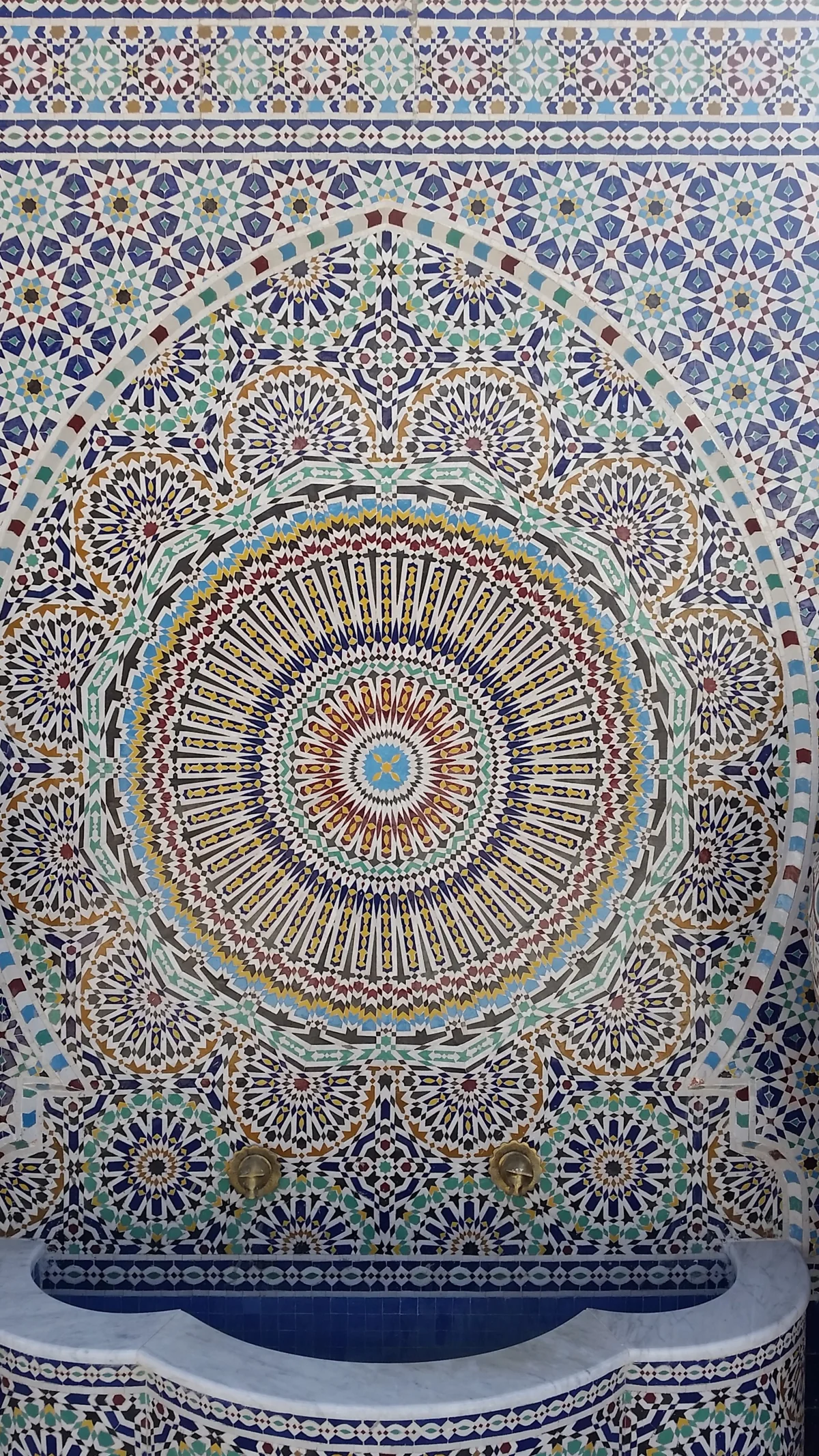 A wall of hand cut glazed zellige tiles in a blue, green and white star pattern