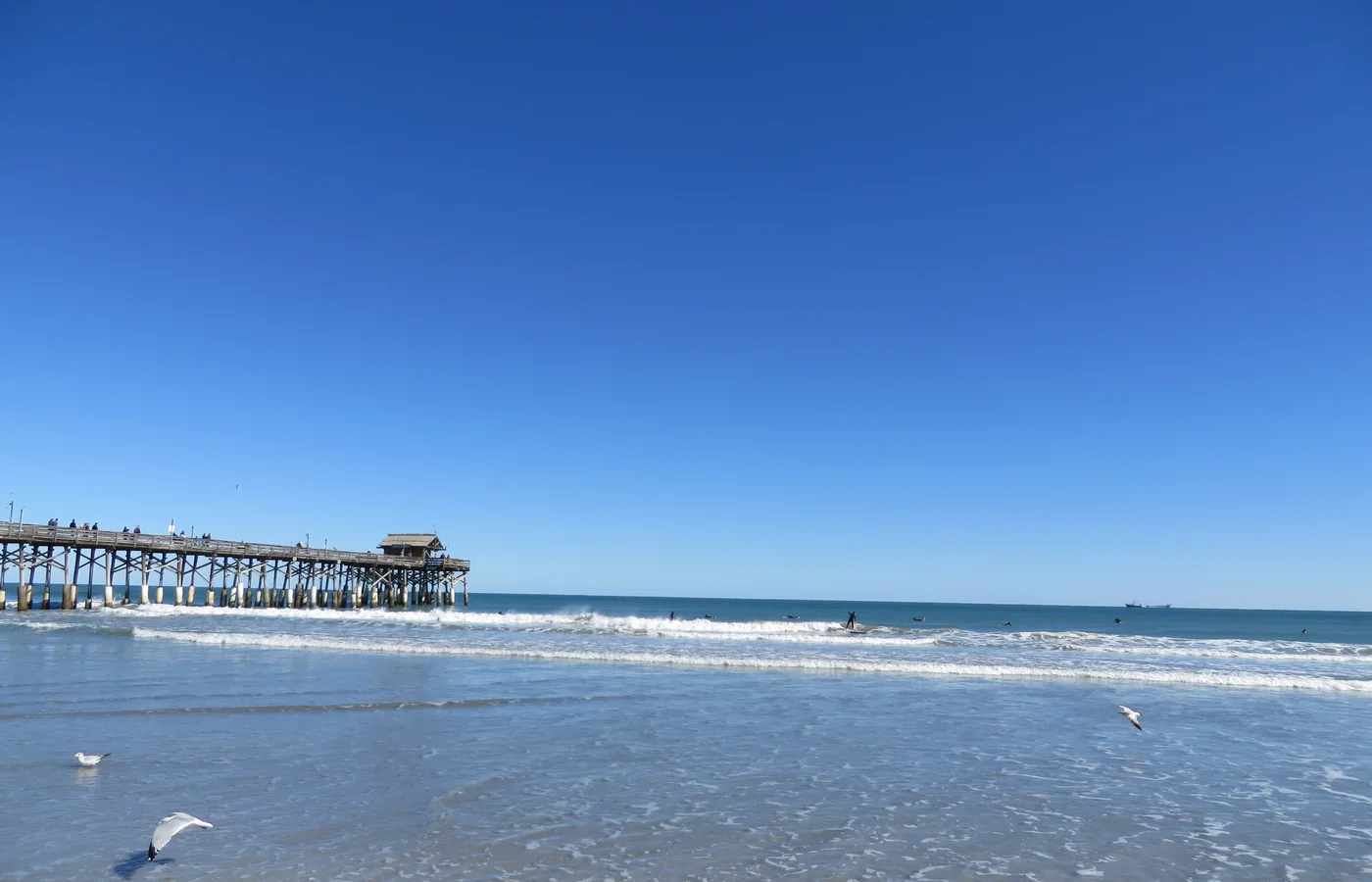 A surfer riding a wave near the Cocoa Beach Pier, Florida