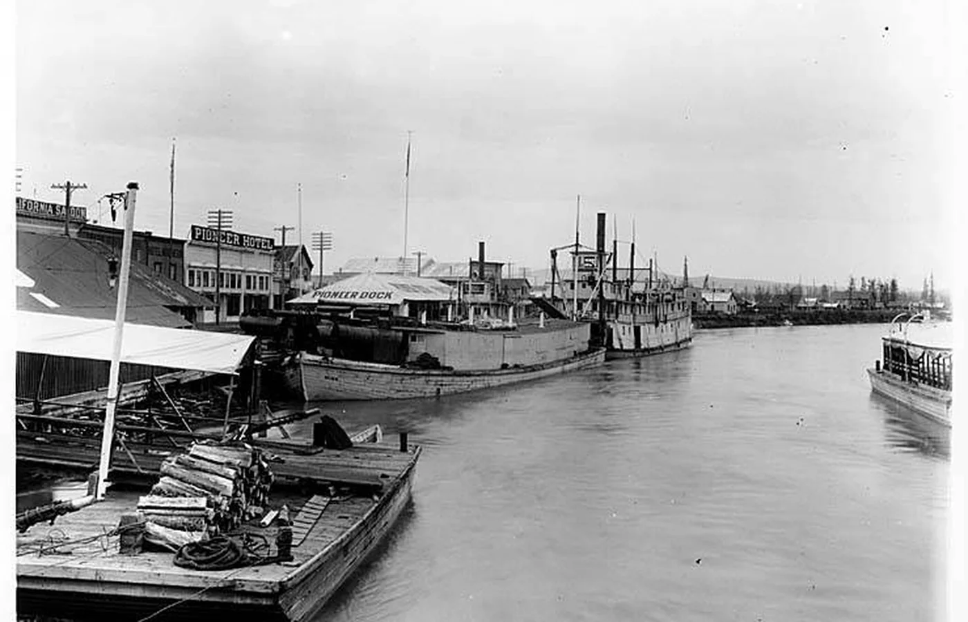 The sternwheel steamer Schwatka and a barge at Pioneer Dock in early Fairbanks, with the California Saloon and Pioneer Hotel behind