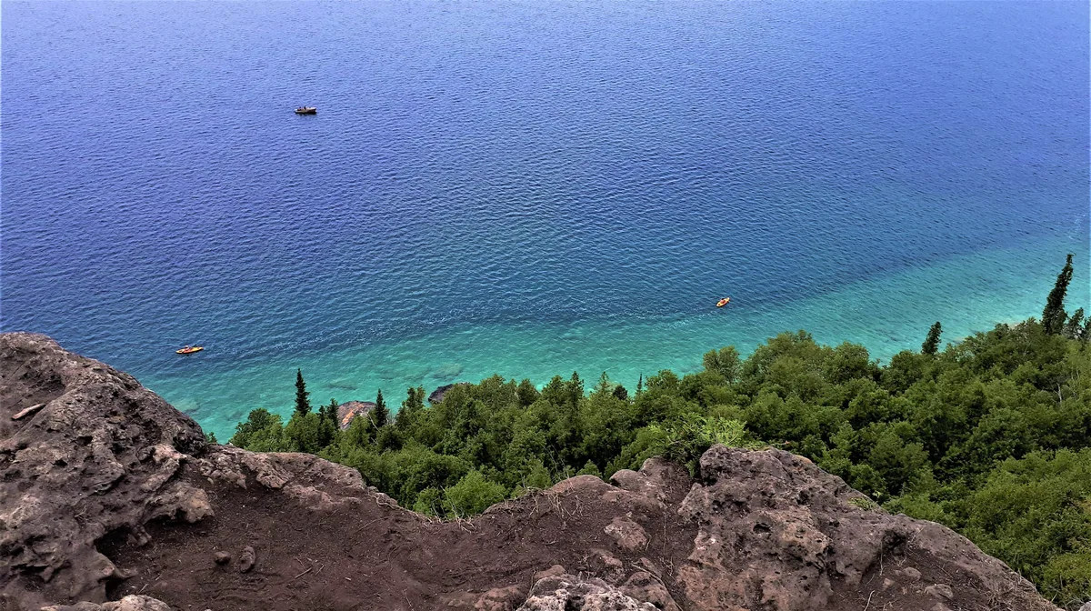 Kayakers on the clear turquoise water of Georgian Bay below the cliffs at the Lion's Head lookout, Bruce Peninsula, Ontario