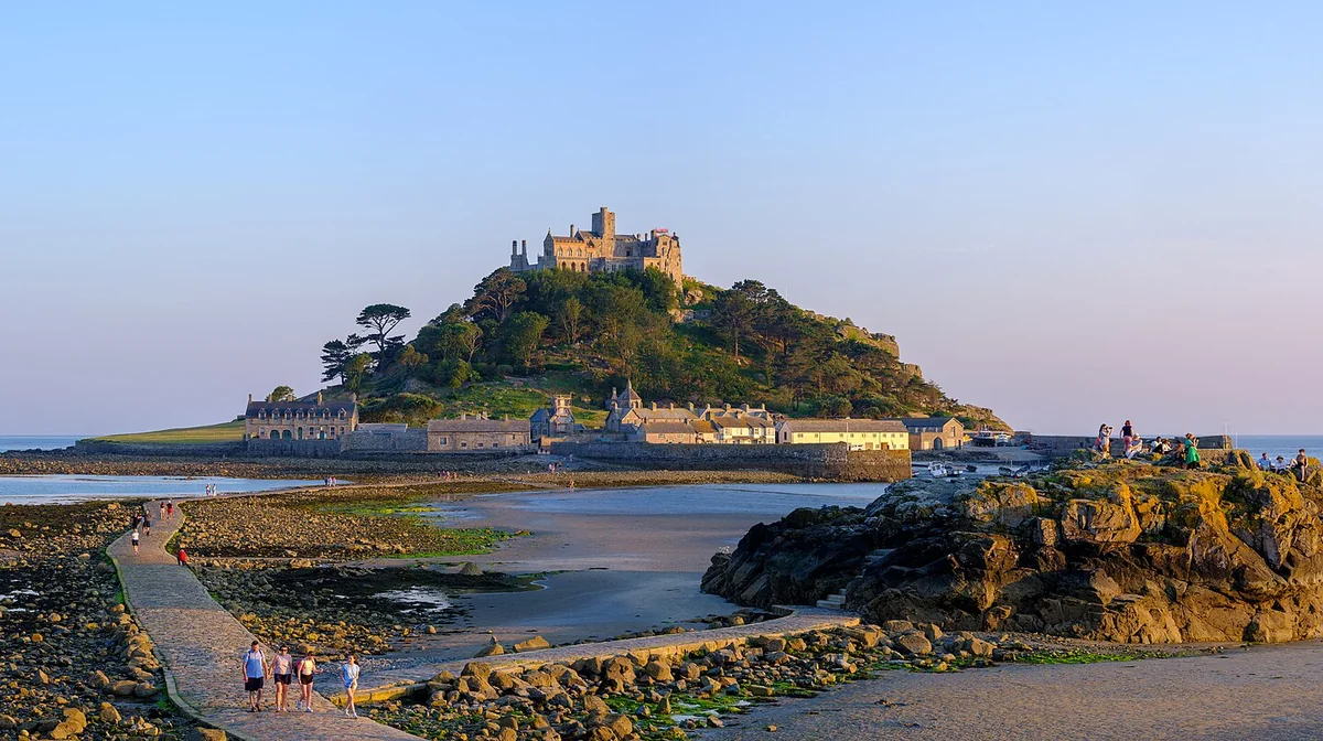 St Michael's Mount at low tide in evening light, with walkers on the stone causeway from Marazion