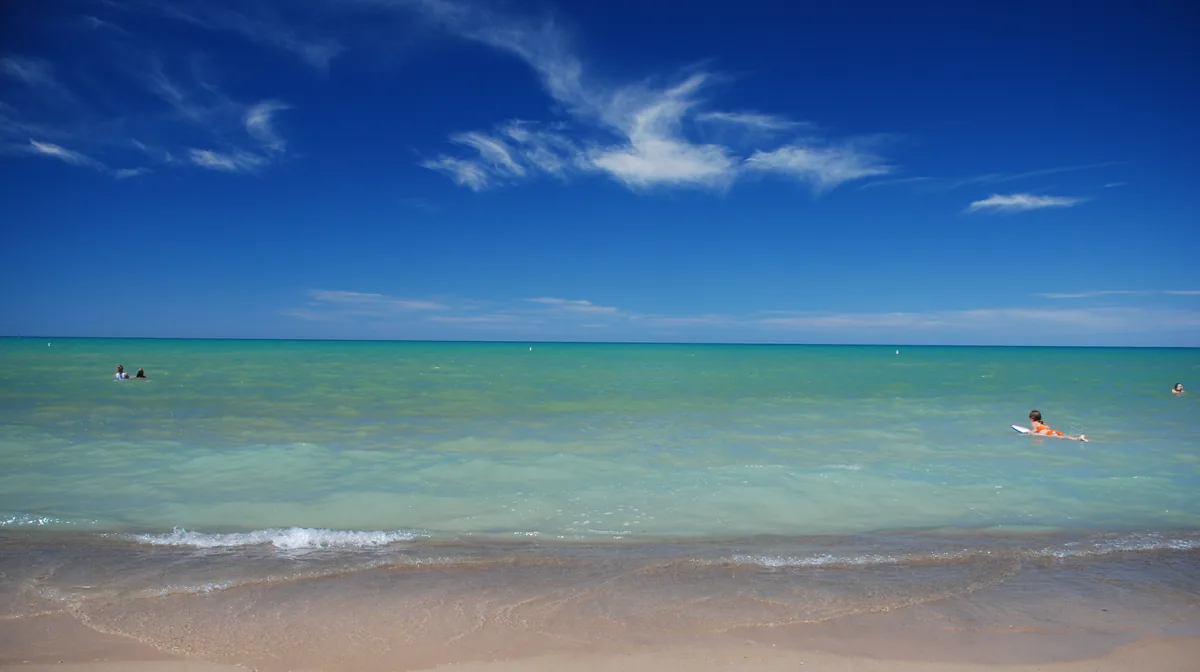 Swimmers in the turquoise water of Lake Huron off Grand Bend's North Beach, Ontario, on a clear summer day