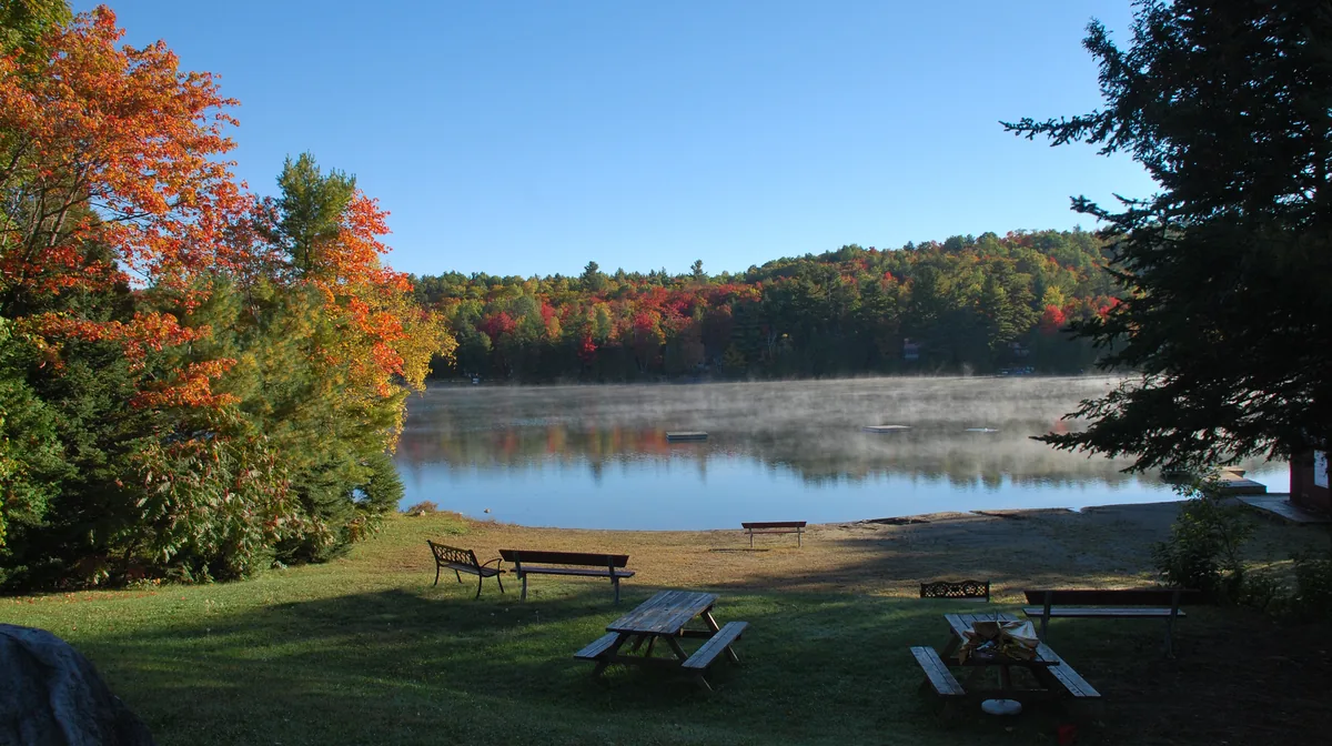 Fall colors and morning mist over a lake beach in Rawdon, Lanaudière, Quebec