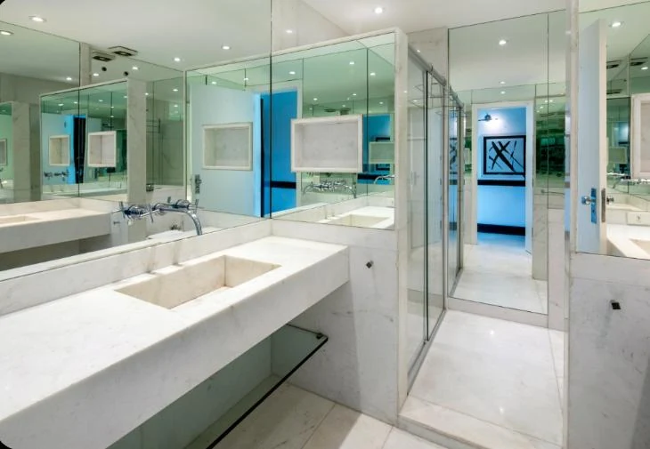 Copacabana penthouse marble bathroom before Cavmir styling — bare vanity, cool blue light, no decor or warmth