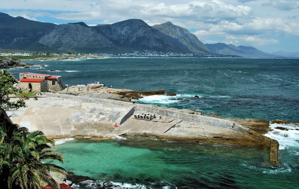 The Old Harbour, a landmark in Hermanus, on Walker Bay, with the town and mountains behind it